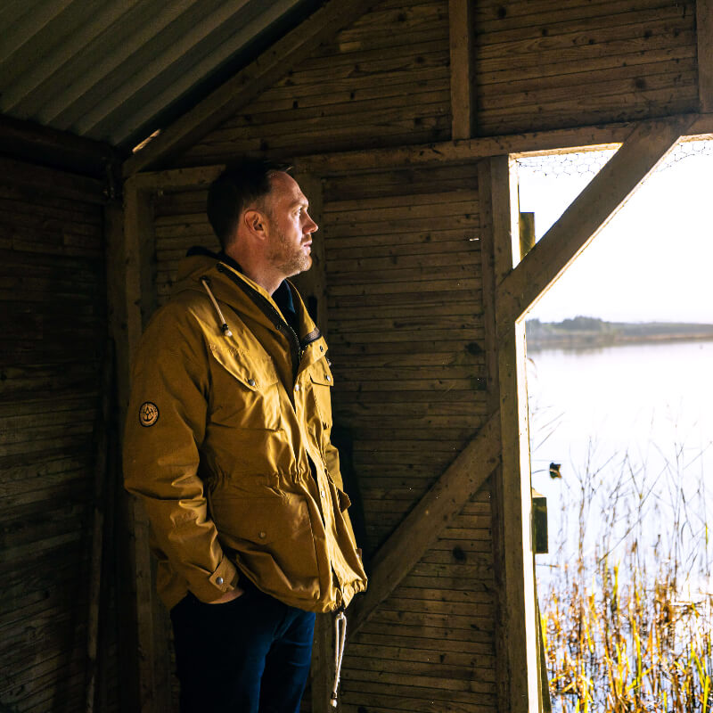 Man wearing Shimi Smock in Cumin in boat barn