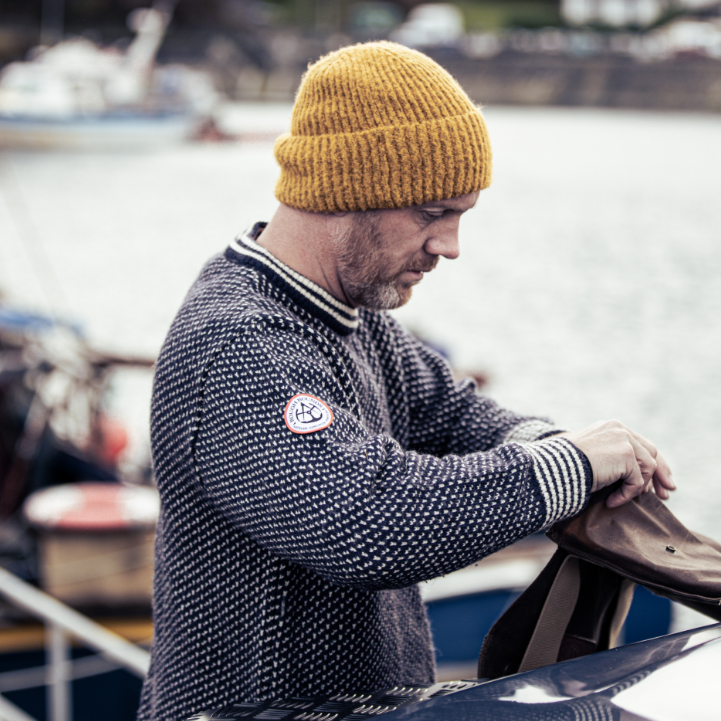 Man packing bag on bonnet of car wearing Gunnerside Sweater