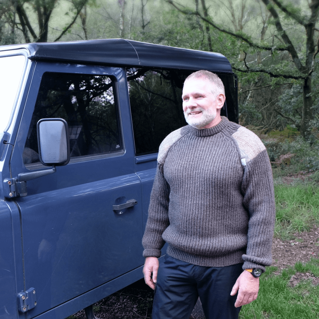 Man standing by a blue Land Rover wearing Rough Bounds Jedburgh Jumper