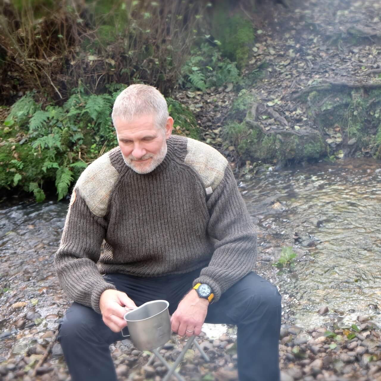 Man sitting by camp fire wearing Rough Bounds Jedburgh Jumper