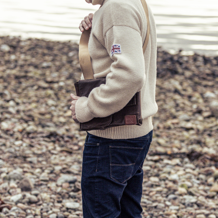 Man wearing Pioneer Bag on his side on pebbled beach